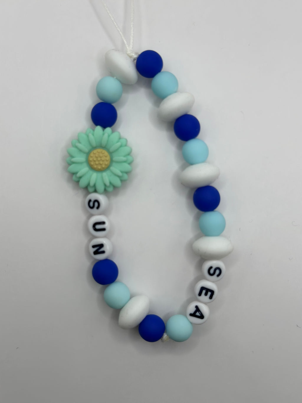 Détail bijou téléphone artisanal perles bleues breloques marines fait main France
