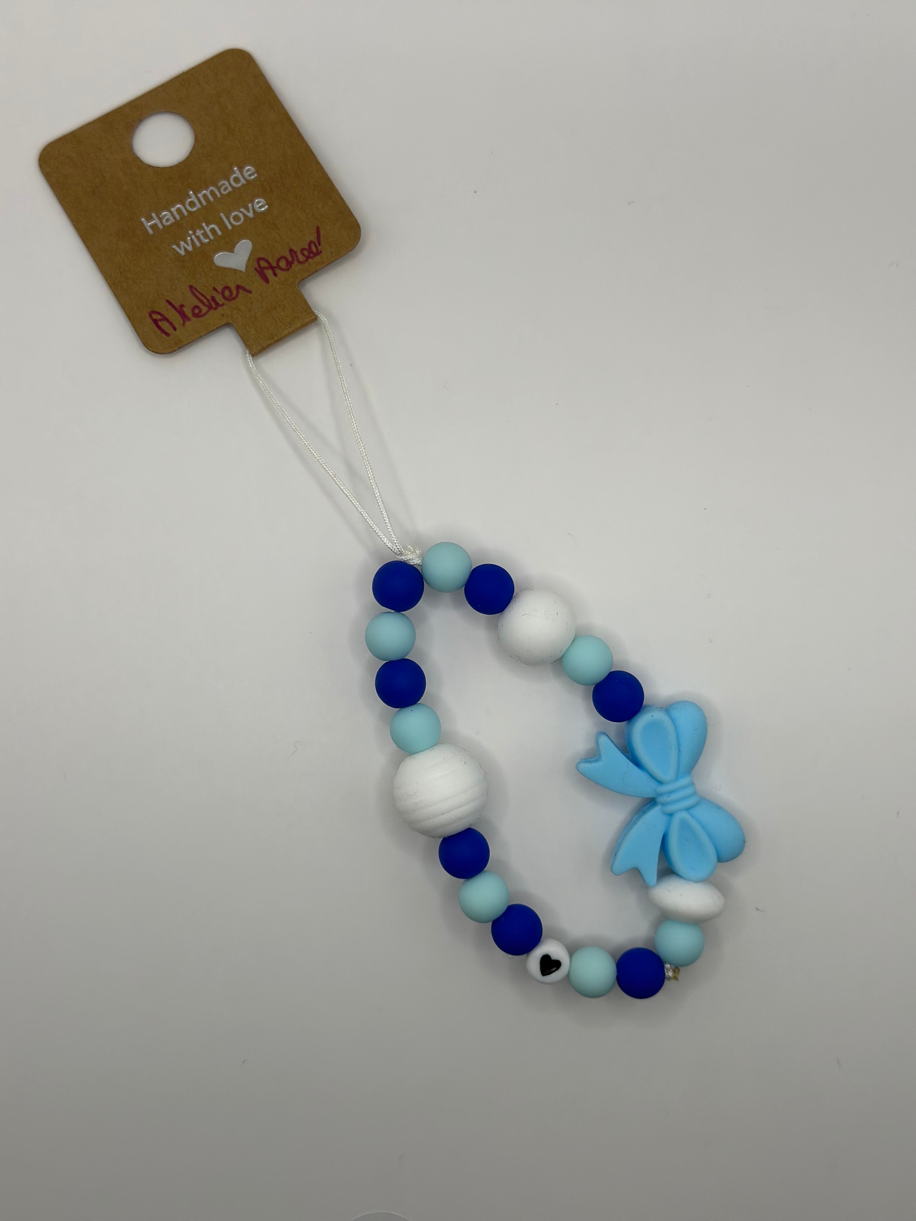 Détail bijou téléphone artisanal nœud bleu perles apaisantes fait main France