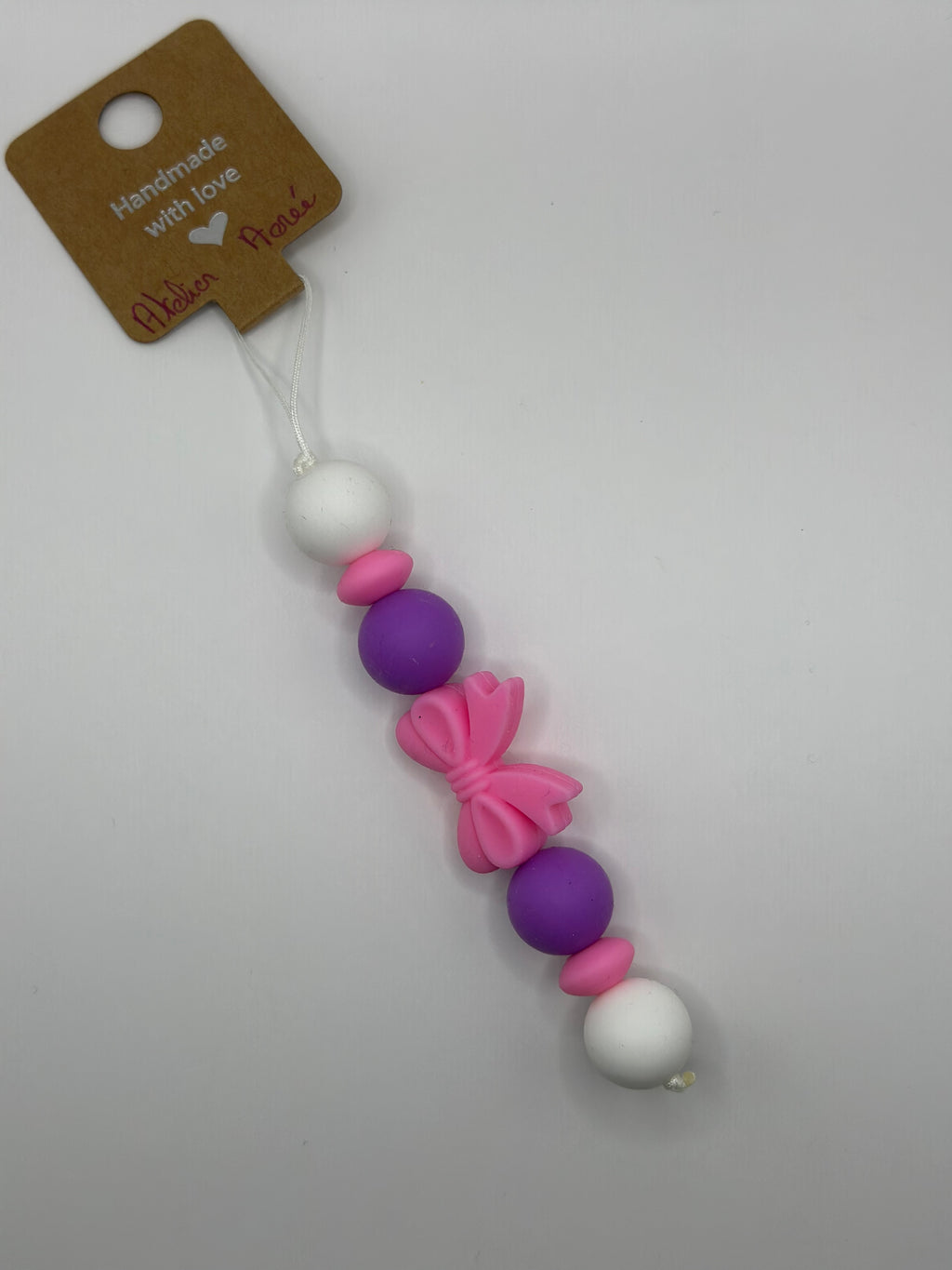 Détail bijou téléphone artisanal noeud rose romantique fait main France 